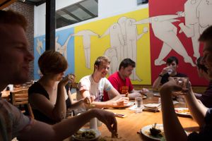 Students seated at tables in a colorful room with art on the walls during a classroom activity.