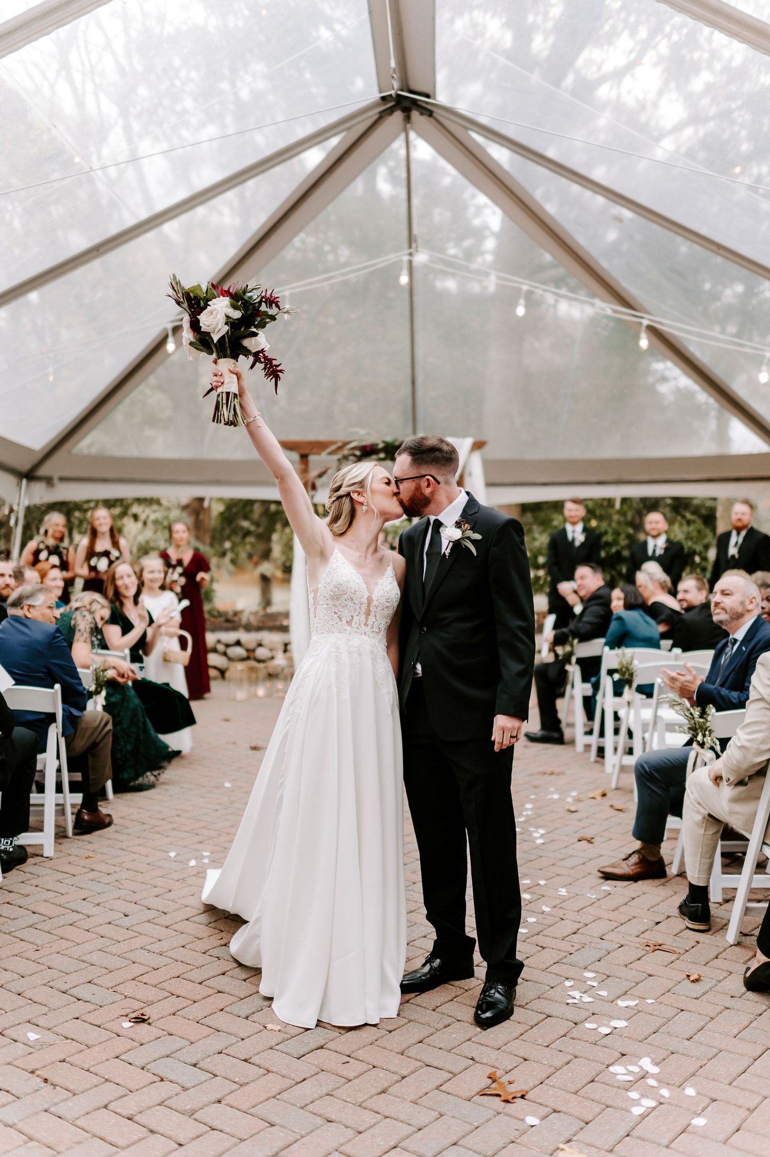 Wedding ceremony under clear tent with guests watching couple's first dance.