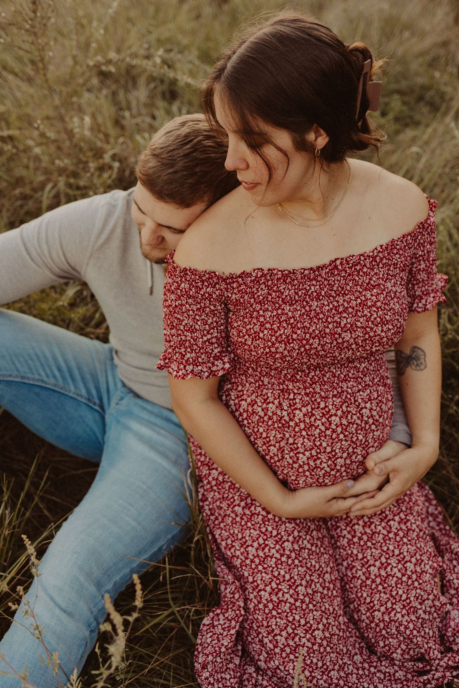 sitting together in an open field maternity session