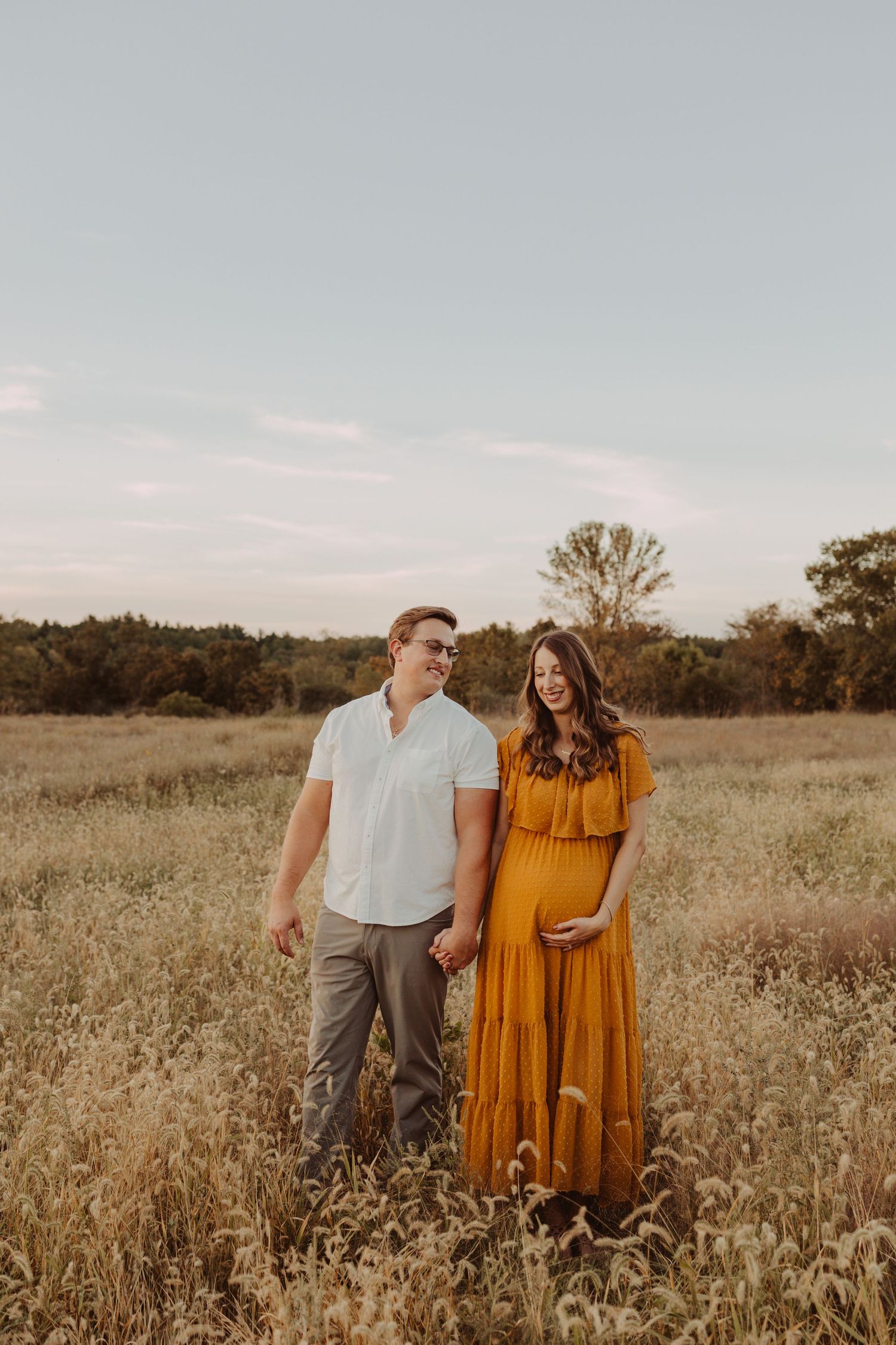 walking in a field with mom and dad maternity photography