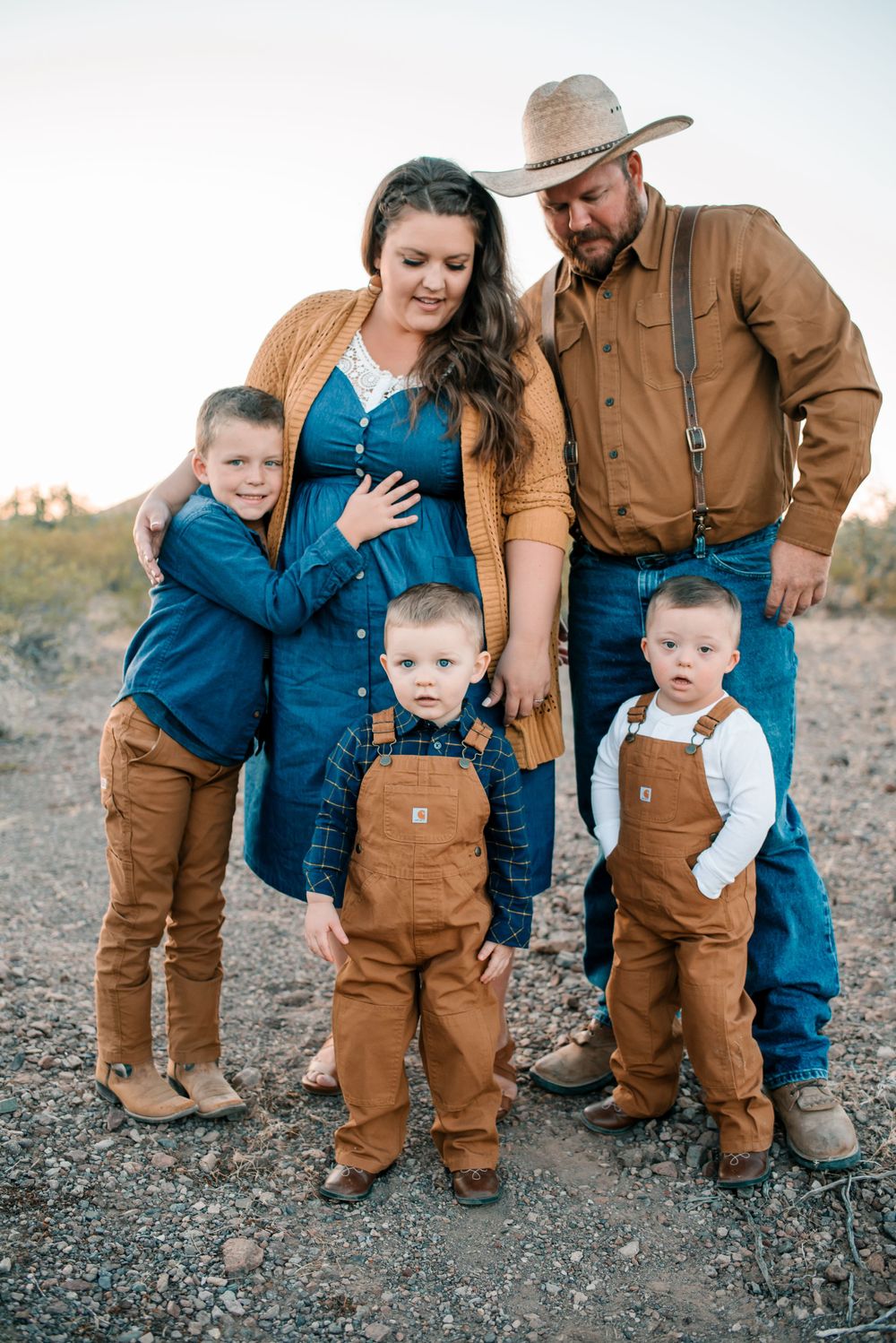 Candid family moment in matching denim and brown overalls against desert backdrop.