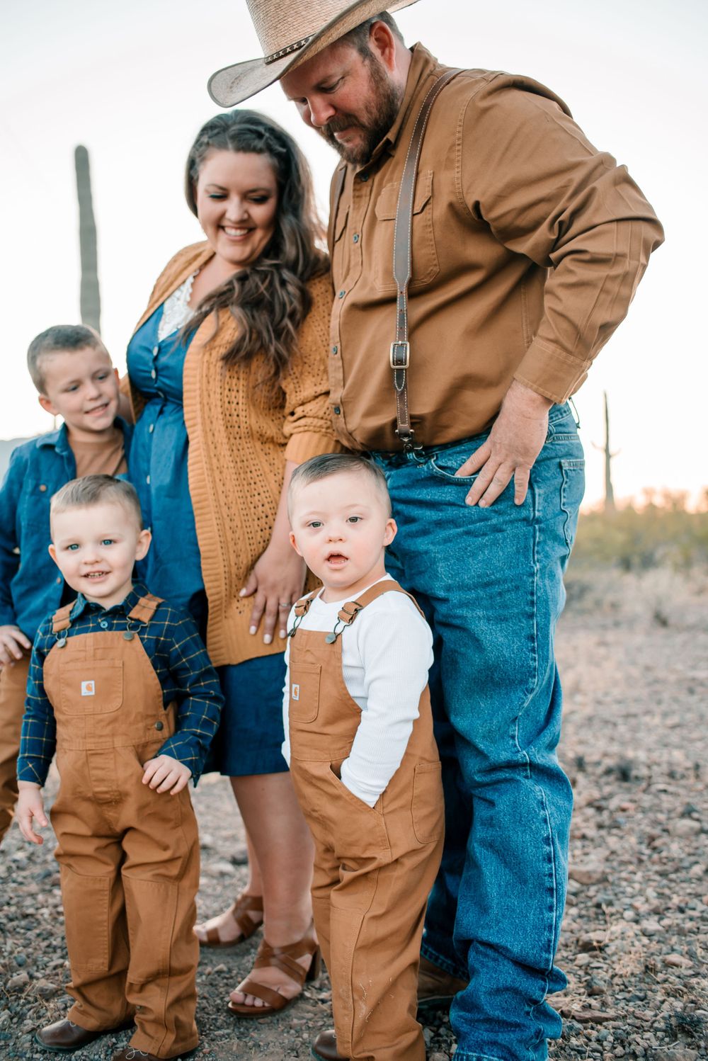 Playful family photo showing coordinated casual western wear in desert setting.