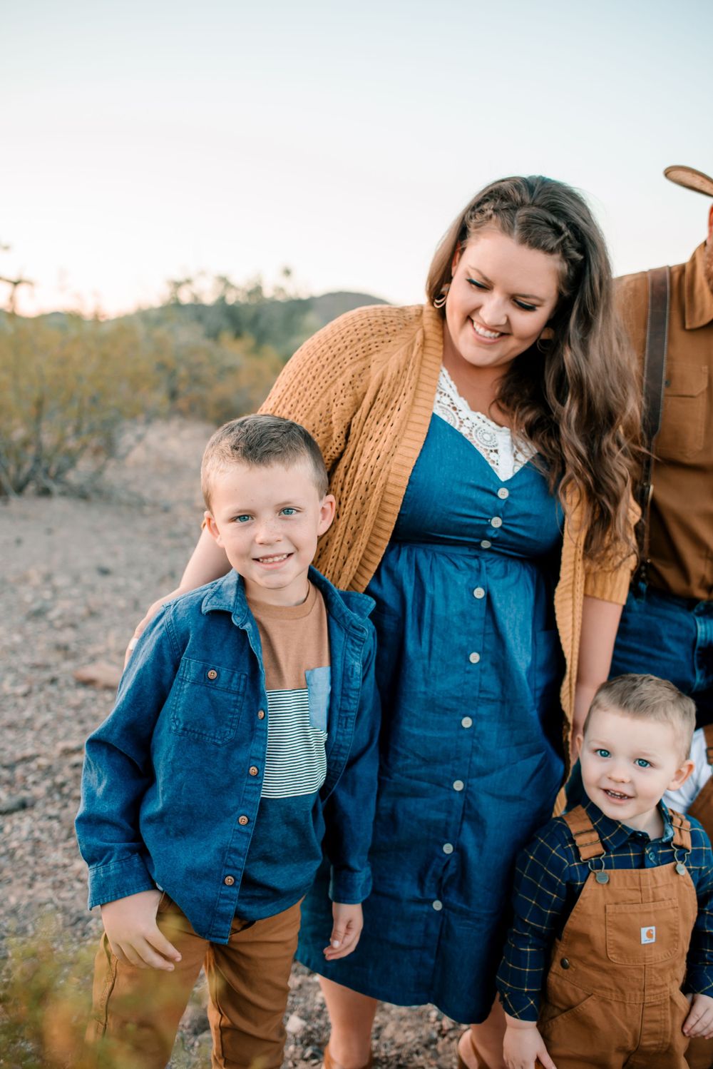 Family members share laughs while wearing coordinated blue and brown outfits in desert setting.