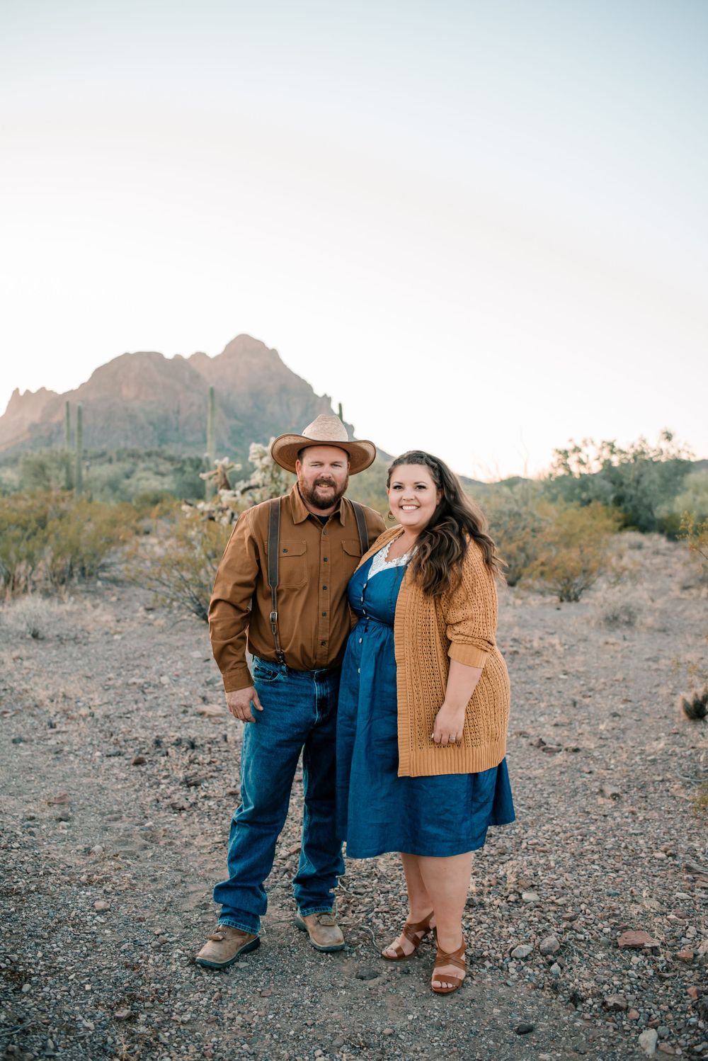 Family in matching western wear poses against mountain backdrop in desert landscape.