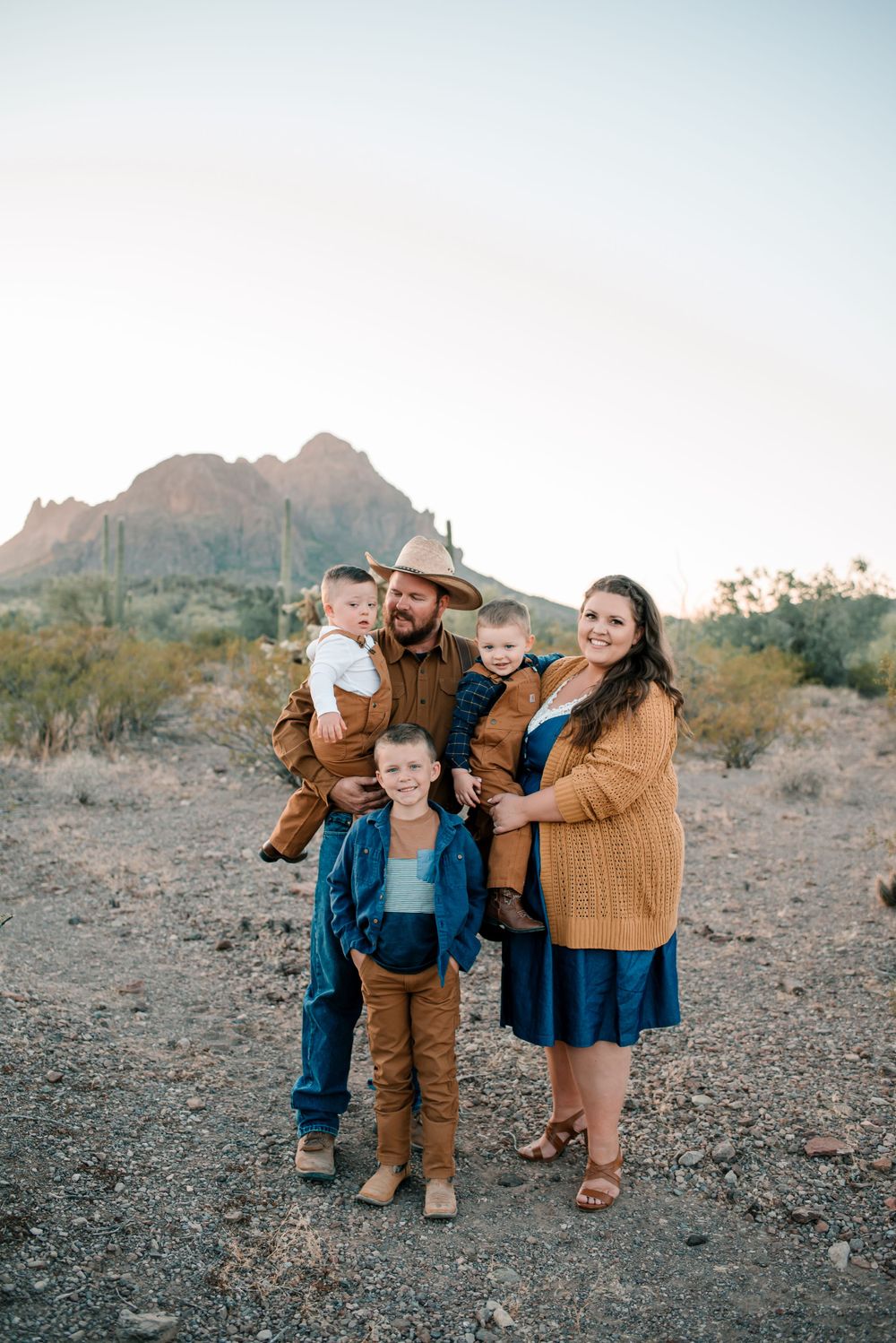 Candid family moments captured in desert setting with matching brown and blue outfits.