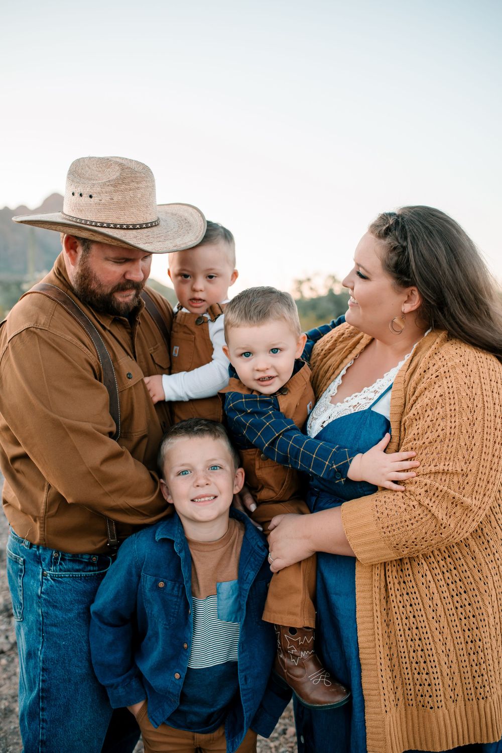 Candid family moment captured in front of rugged desert mountains during sunset.