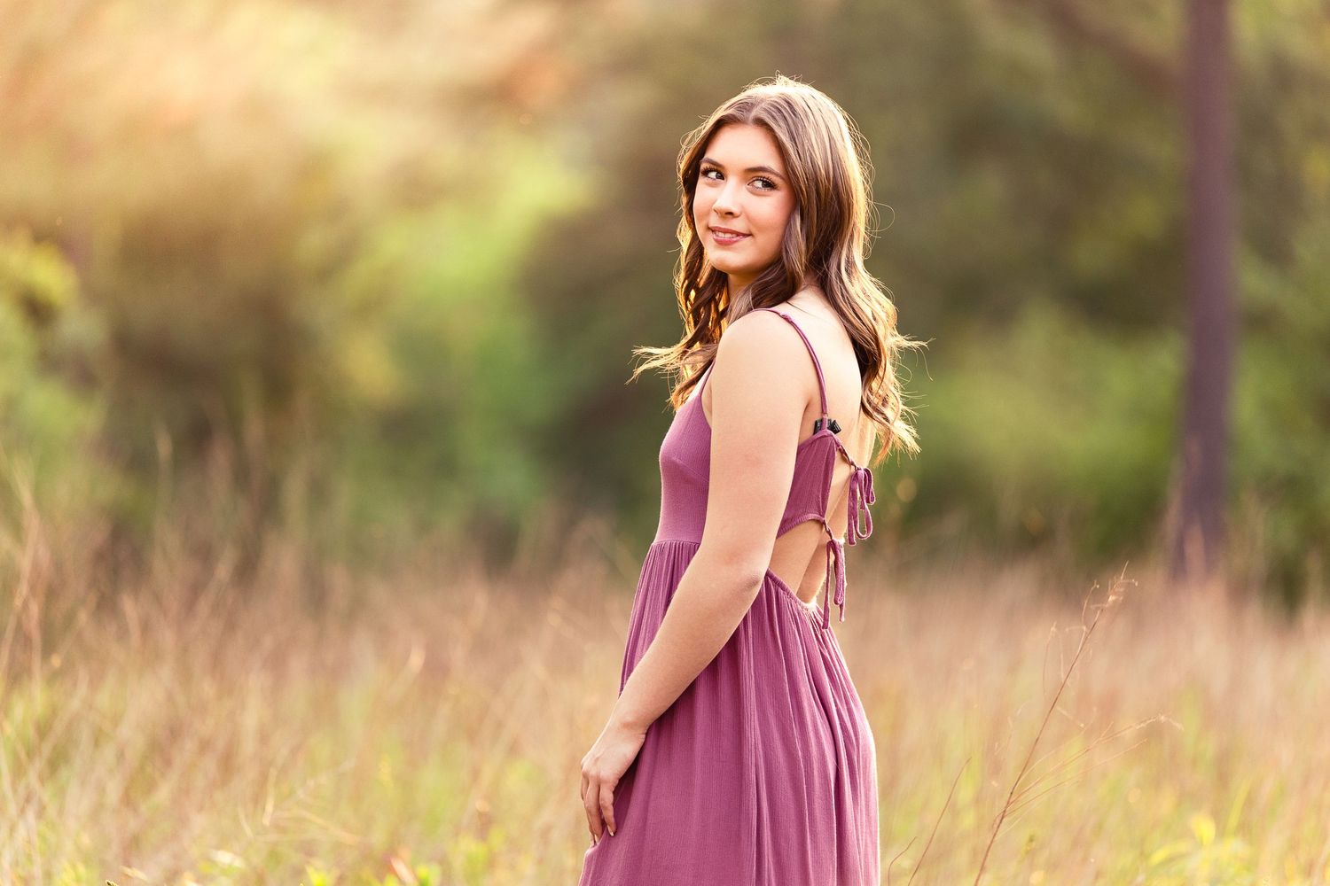 A dreamy outdoor portrait in a mauve dress with sunset meadow backdrop.