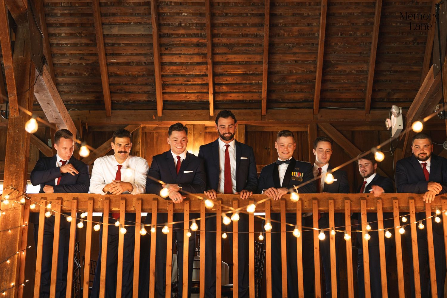 Group photo of wedding party members posing on rustic wooden balcony.