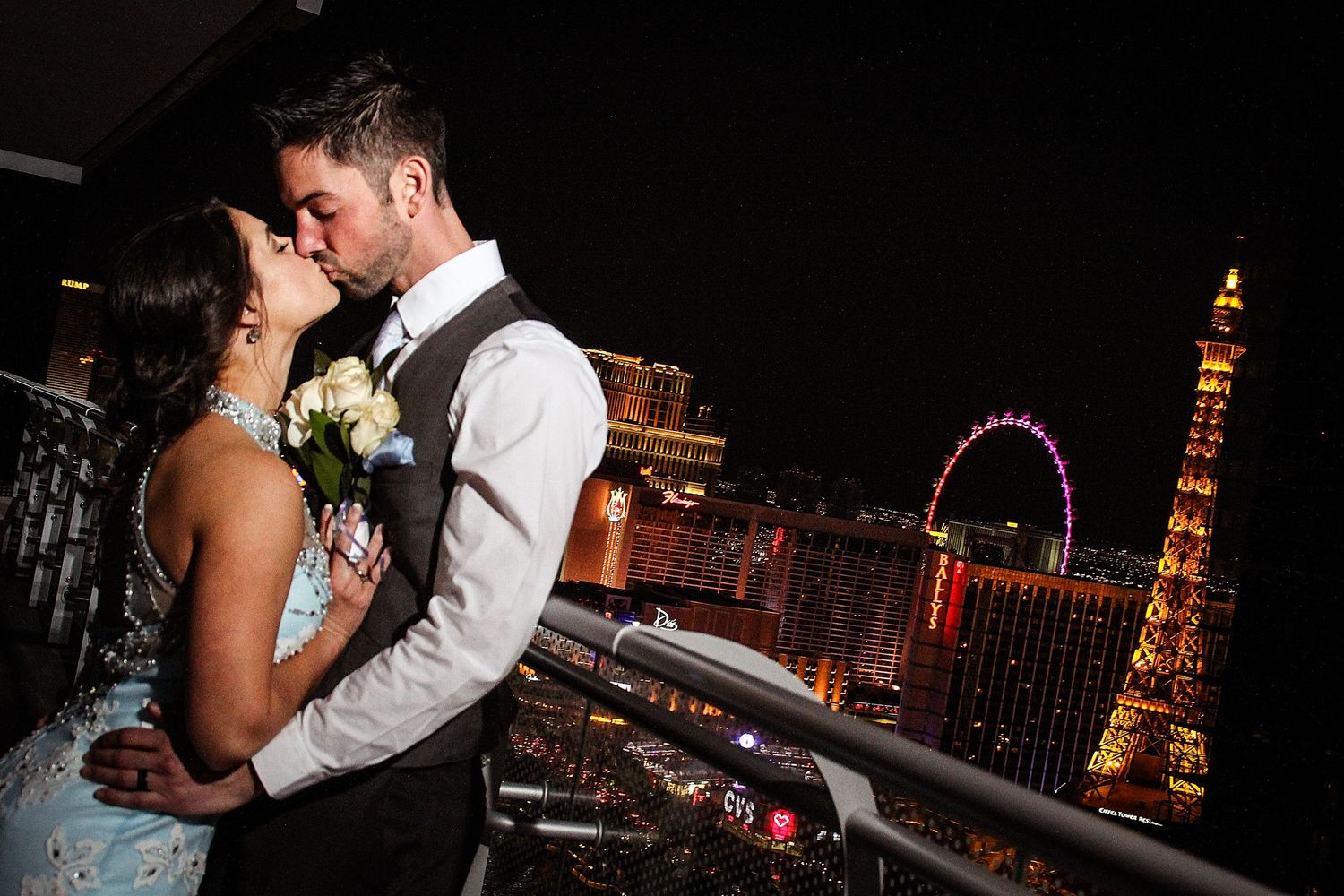 A romantic nighttime kiss with the Las Vegas Strip lights glowing in the background.