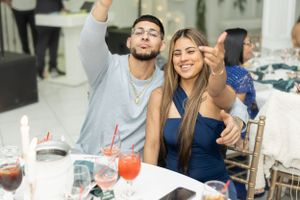 Party guests raising their arms in celebration at a formal dining table with cocktails.