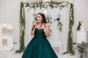 A performance in front of a floral arch backdrop at an elegant celebration.
