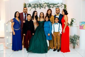 Family group photo at formal event with guests wearing elegant dresses and suits.