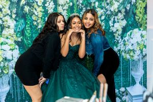 Friends having fun posing for photos against floral backdrop at formal event.