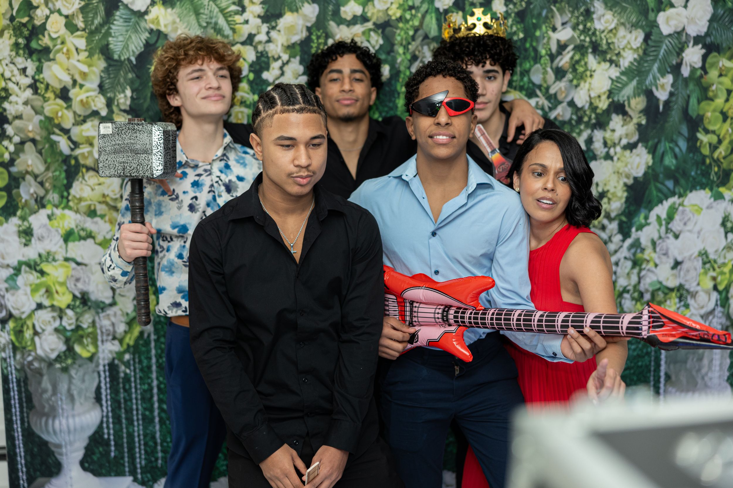 Musicians with instruments pose against a floral backdrop at an event.
