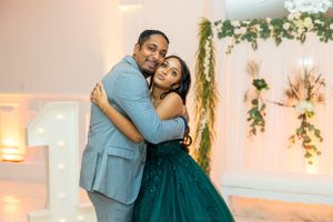 A couple sharing an embrace at a special event with floral decor and soft lighting.