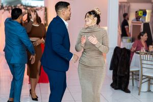 Couple dancing in formal attire at elegant event with burgundy suit and red dress.