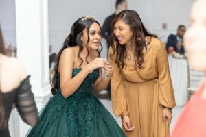 Two women sharing a joyful moment, one wearing an emerald green gown at a formal event.