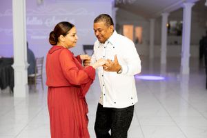 Two people sharing an animated conversation on a dance floor with purple ambient lighting.