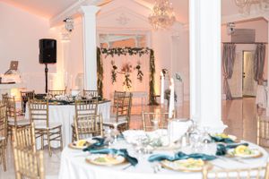Wedding reception venue with gold chairs and floral arch setup for an elegant celebration.