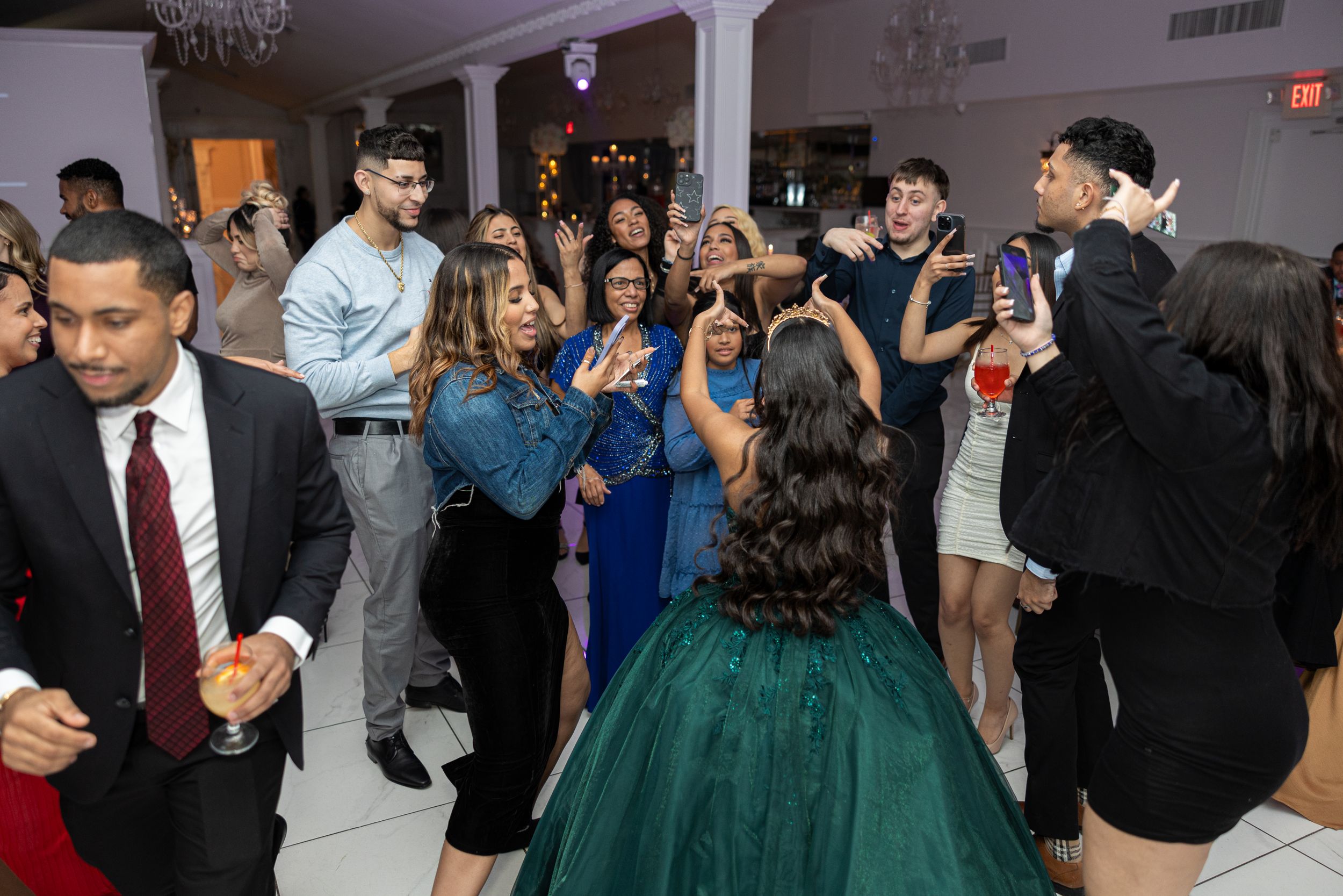 Guests celebrating at an elegant party with someone wearing a stunning emerald green ballgown.