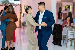 Couples enjoying dance moves at formal celebration in elegant venue with pink walls.