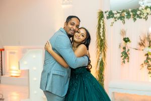 Happy couple embracing and smiling during a celebration in front of decorative floral arrangements.