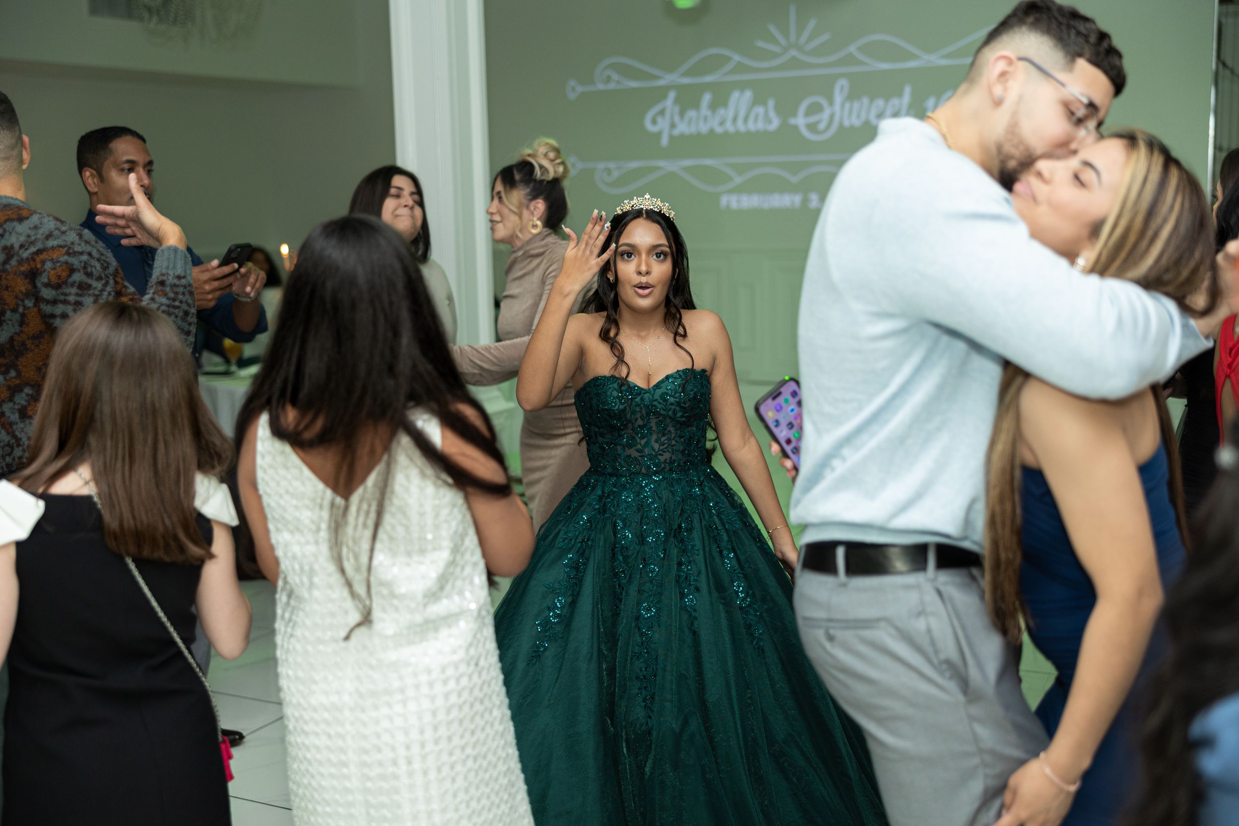 Partygoers dancing and celebrating around someone in a sparkling emerald green gown.