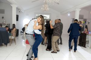 Couples sharing dance moves at formal celebration in white elegant venue.
