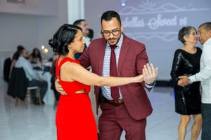 Dance partners in burgundy suit and red dress sharing an elegant moment on dance floor.