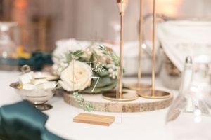 Elegant table centerpiece with white flowers and gold candlesticks on wooden base.