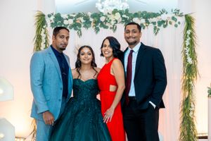 Formal group portrait with guests in elegant attire against floral backdrop.