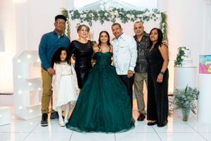 Family gathering for group photo at formal celebration with emerald green ball gown centerpiece.