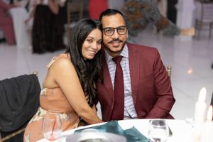 Well-dressed couple posing together at formal indoor celebration.