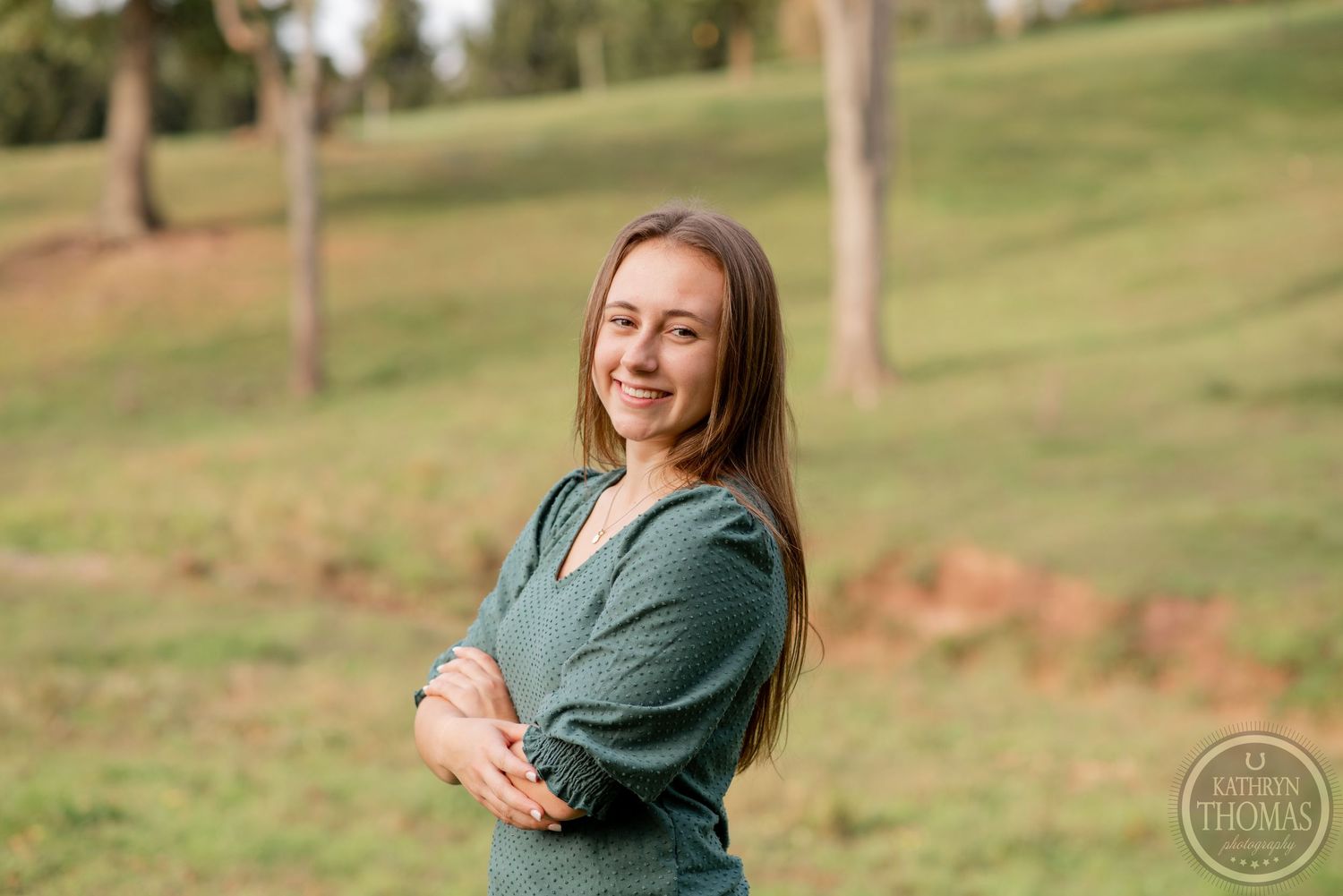Portrait in green sweater against pastoral hillside background.