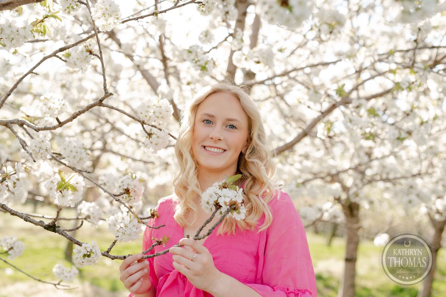 Spring portrait among blooming cherry blossoms in bright sunlight.