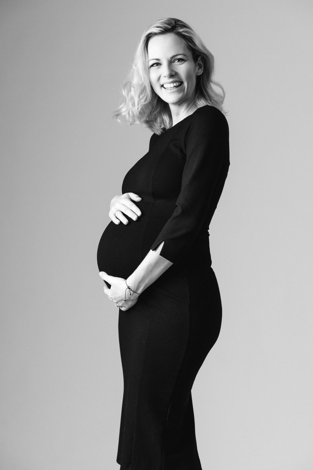 Maternity photo sequence showing pregnancy progression in black and white studio setting.