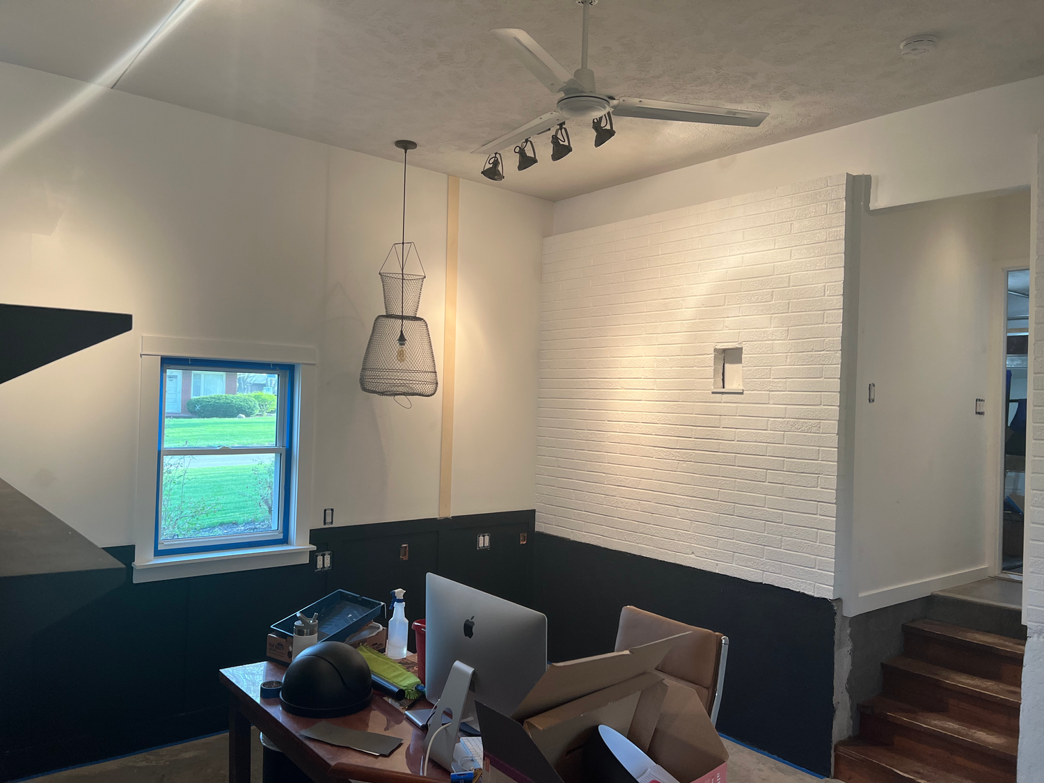 Contemporary workspace with white brick walls, pendant lighting and wooden stairs.
