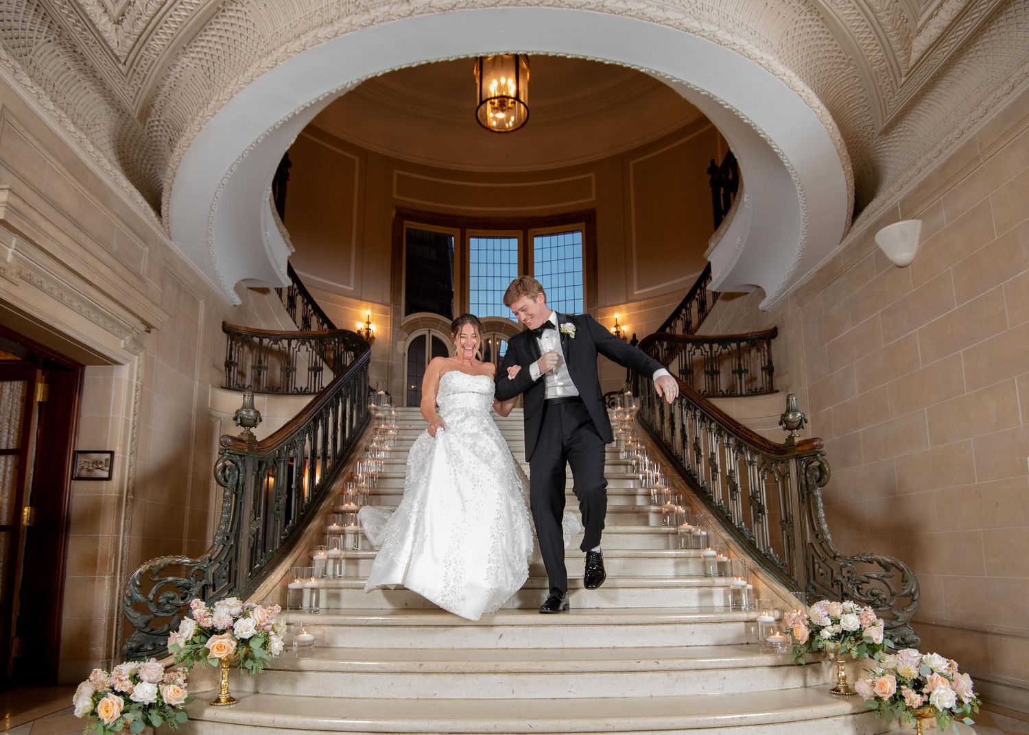Grand marble staircase decorated with floral arrangements in an elegant venue setting.