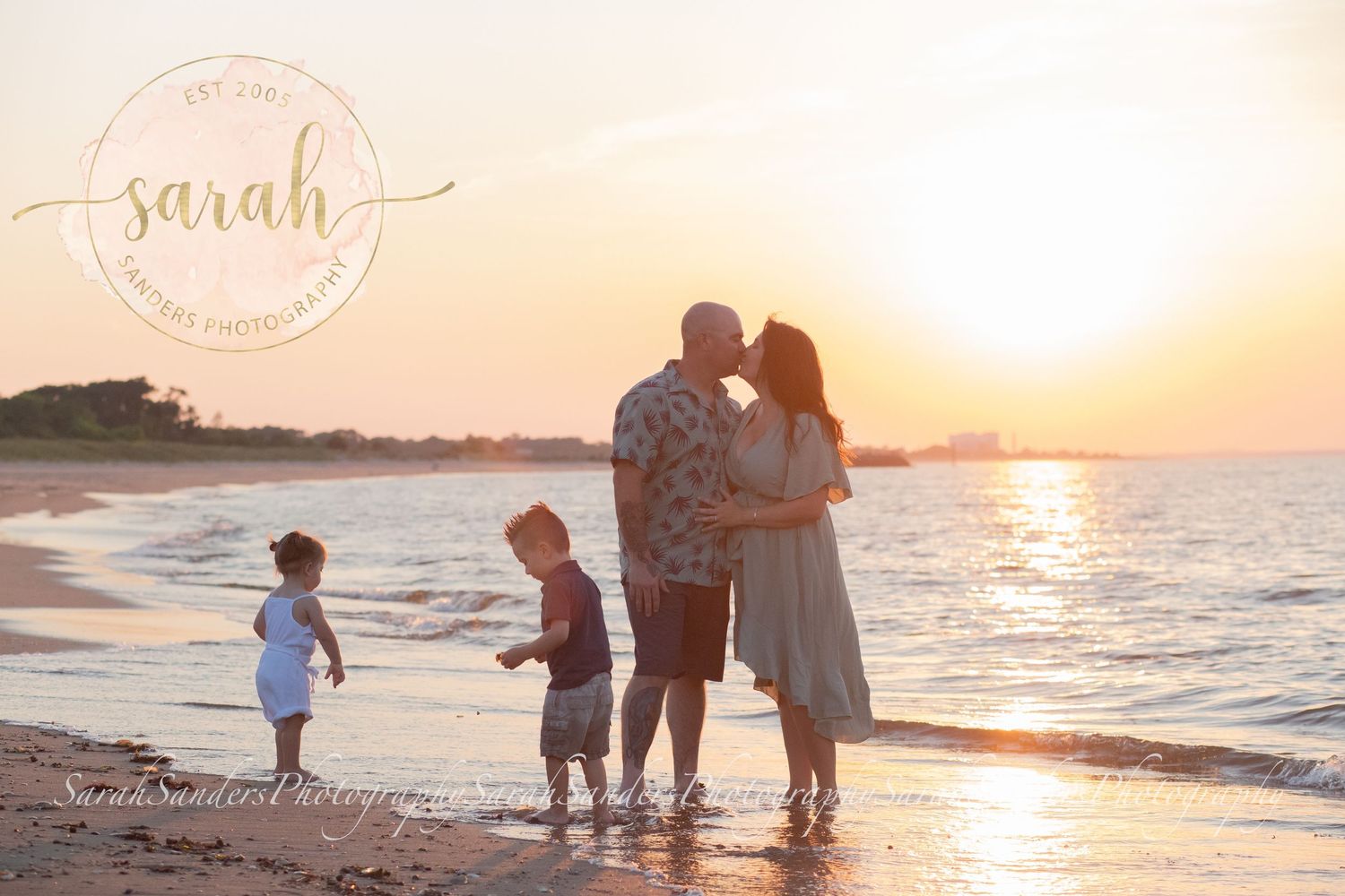 Family standing at the beach during sunset, kids playing