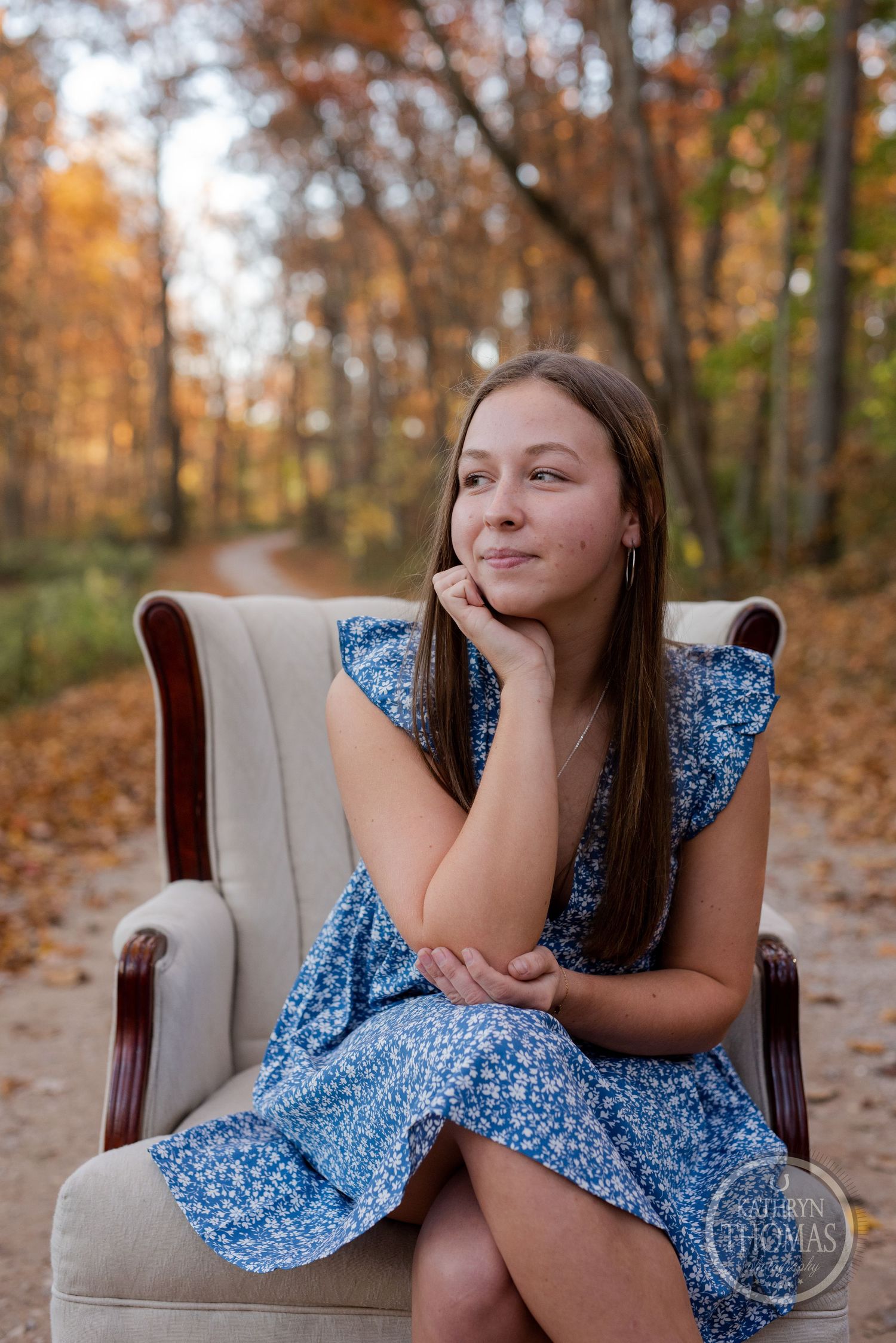 A relaxed autumn portrait session featuring a blue floral dress and beige armchair in the woods.