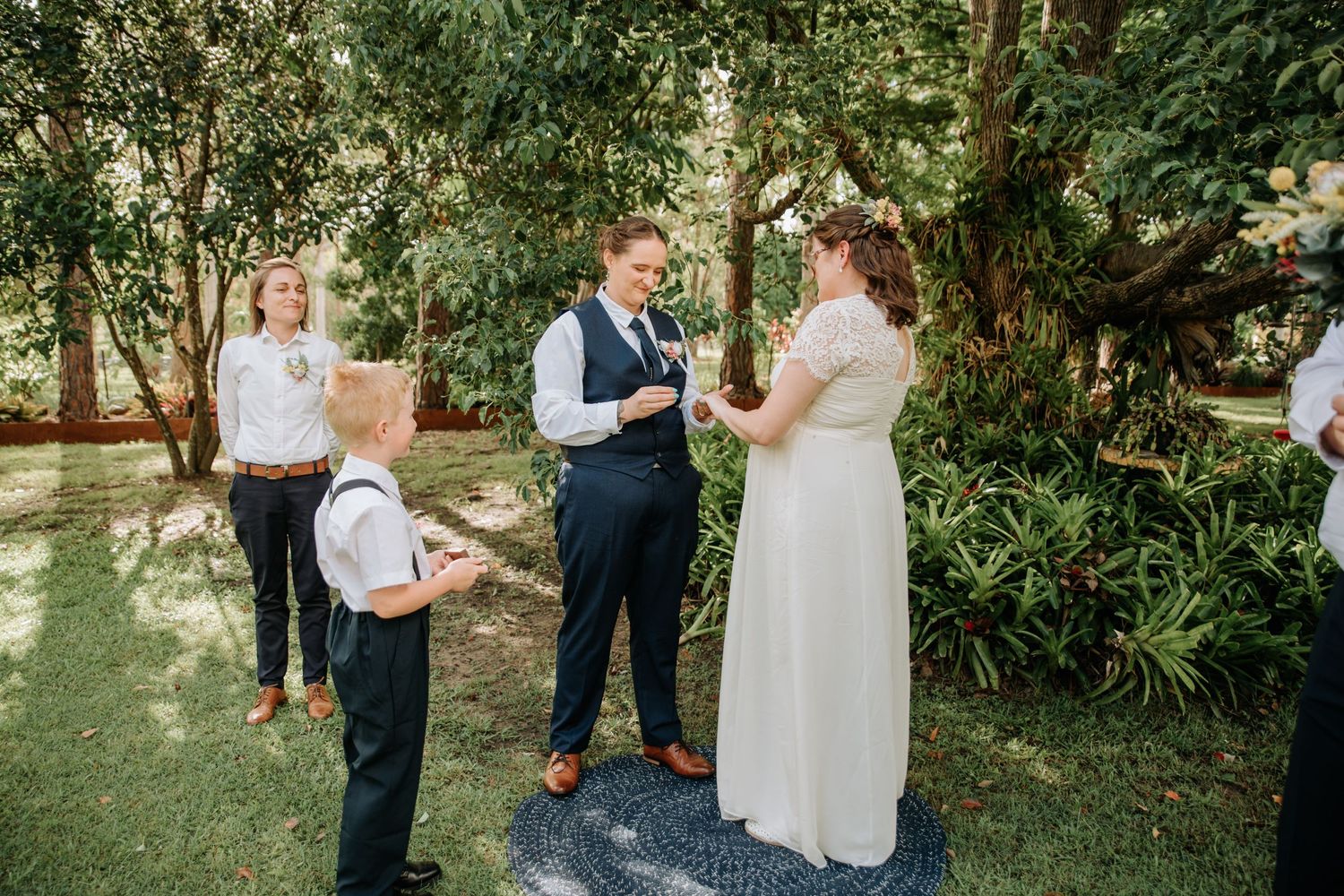 An intimate outdoor wedding ceremony taking place in a garden surrounded by lush greenery.