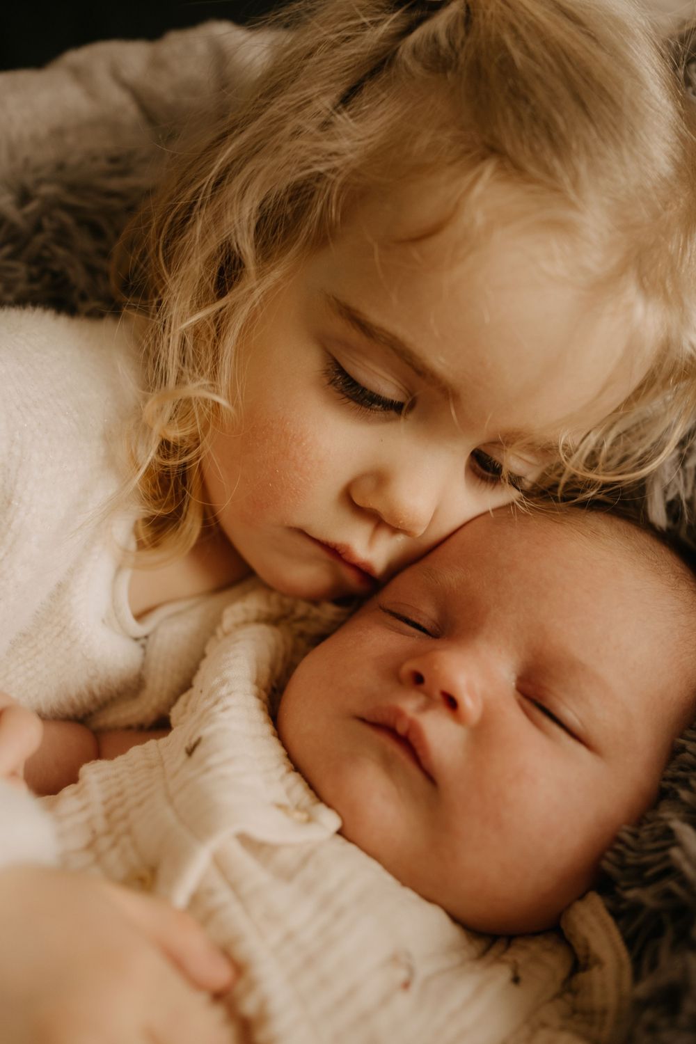 Heartwarming moment of siblings sleeping peacefully together on cozy bedding.