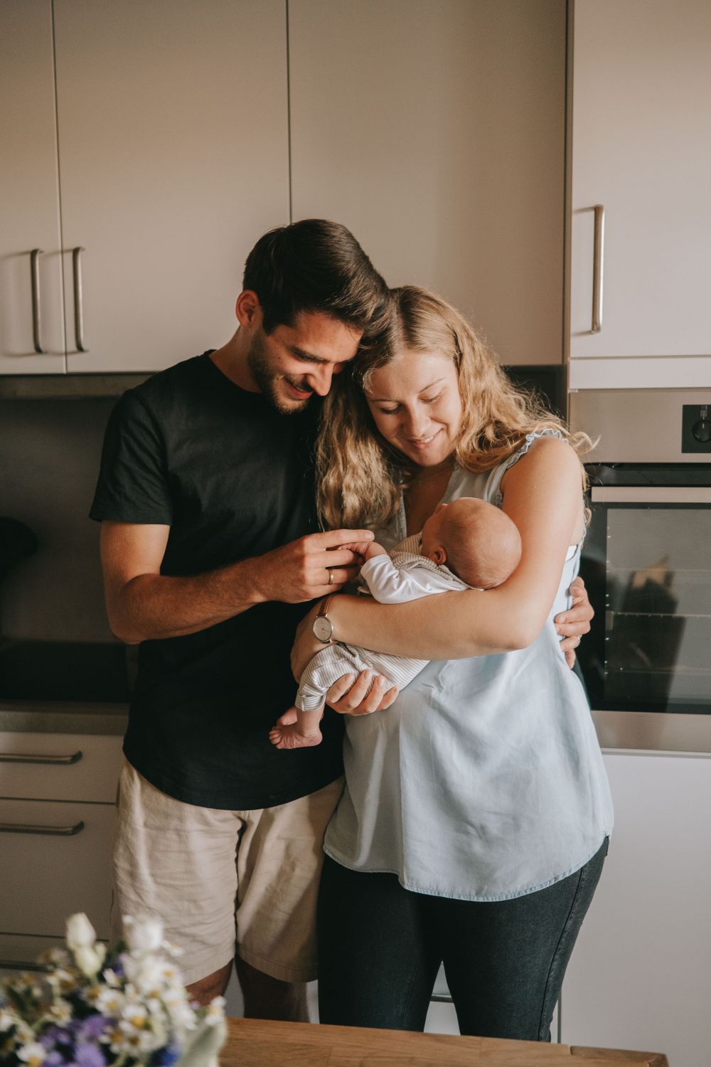 Tender family moment in kitchen as couple shares joy with their newborn.