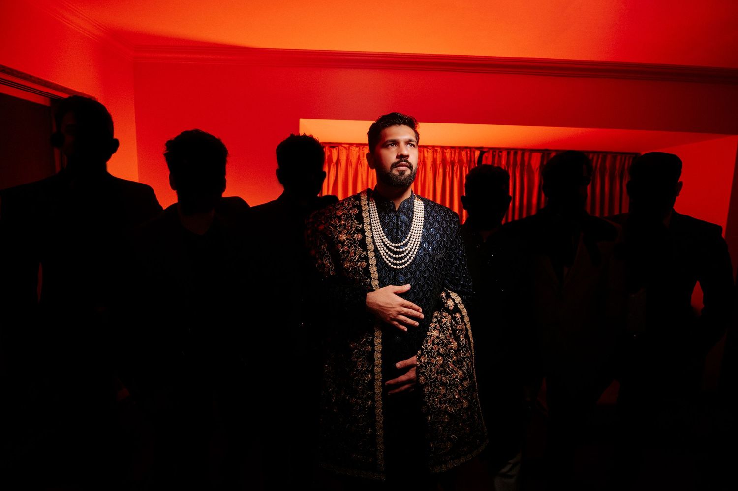 Dramatic silhouette of wedding guests against a vibrant red background.