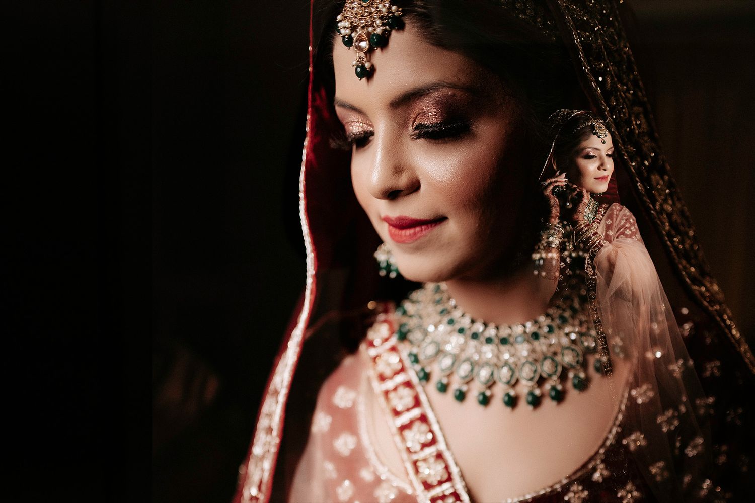 Close-up shot highlighting ornate bridal jewelry and traditional Indian wedding makeup.