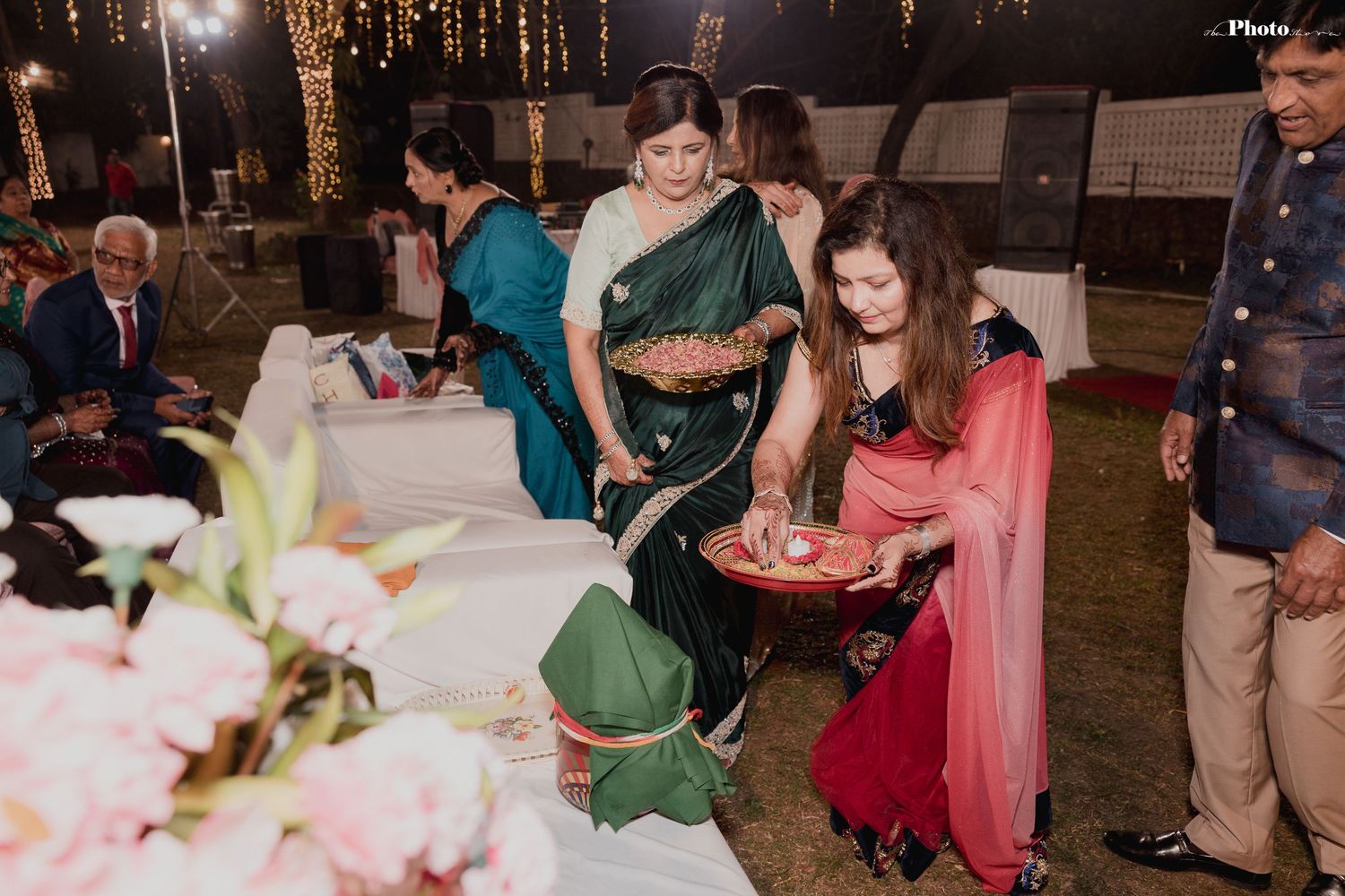 Wedding reception scene with guests gathered around decorated tables.
