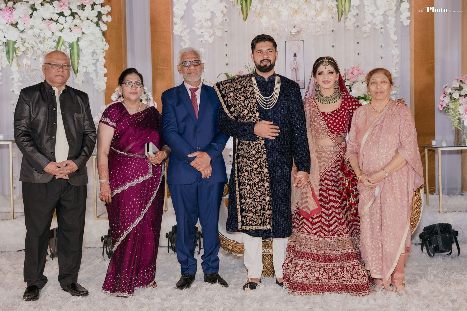 Large family group photo at wedding celebration with traditional South Asian formal wear.