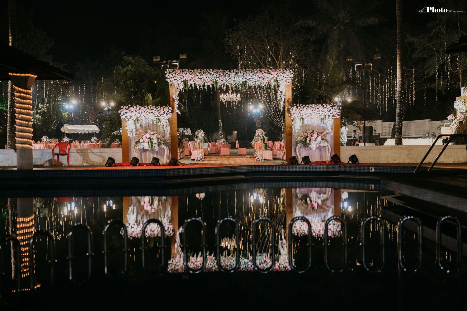 Elegant wedding stage decor with illuminated panels reflecting in a pool at night.