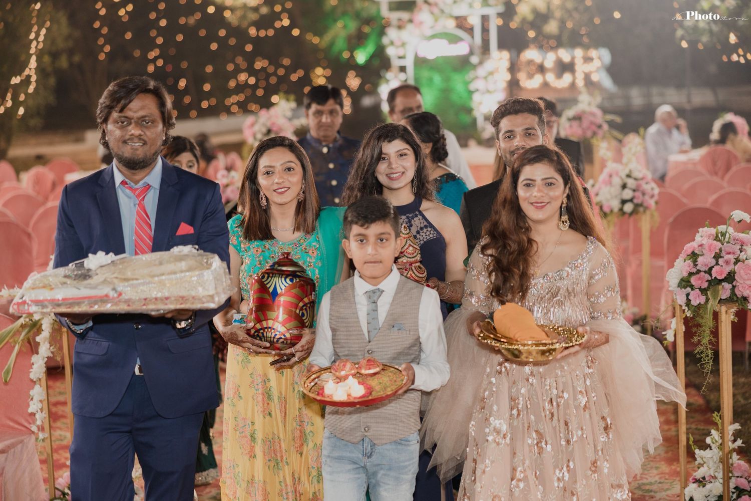 Wedding reception gathering with guests mingling in formal attire under decorative lighting.