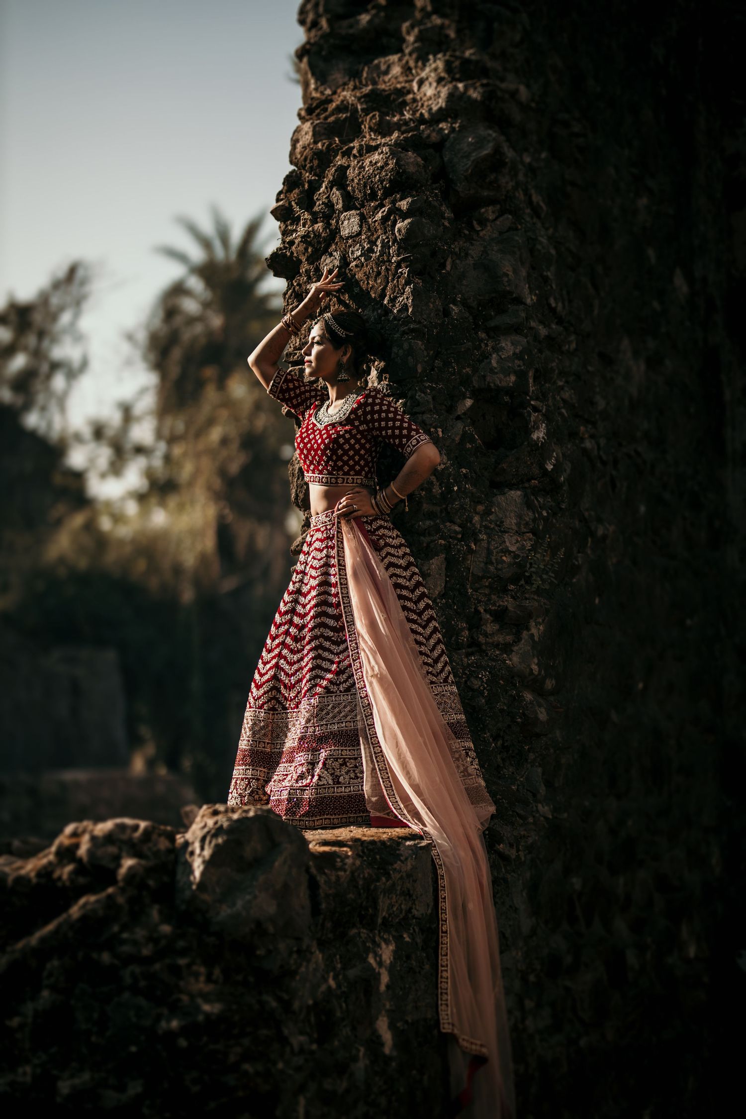 Artistic wedding portrait captured during golden hour with rocky landscape backdrop.